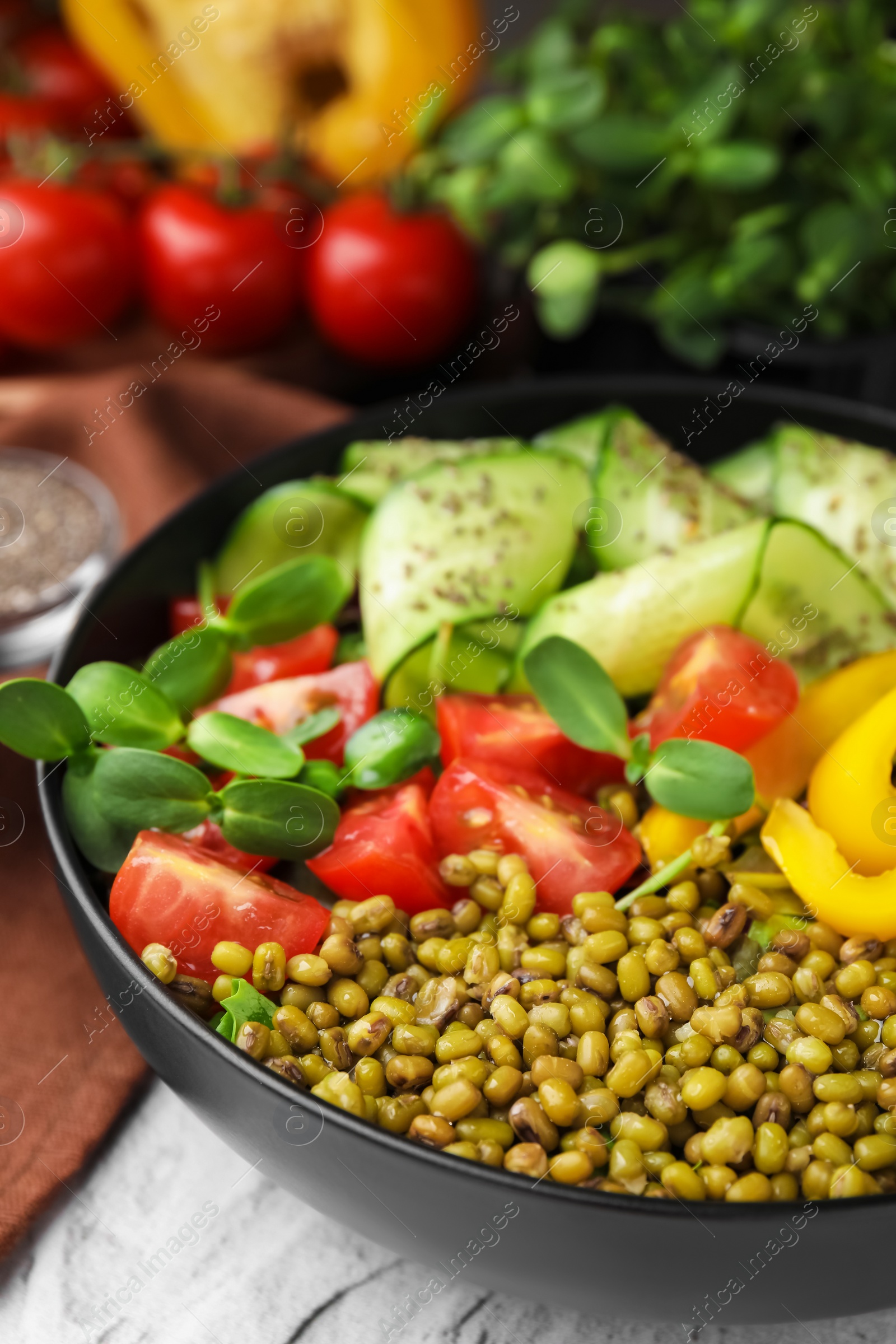 Photo of Bowl of salad with mung beans on white textured table, closeup