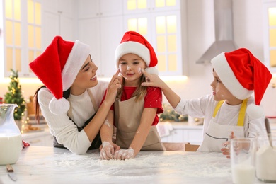 Photo of Mother with her cute little children having fun while making Christmas cookies in kitchen