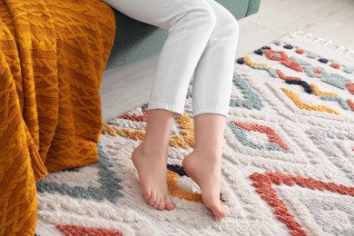 Photo of Woman on carpet with pattern at home, closeup