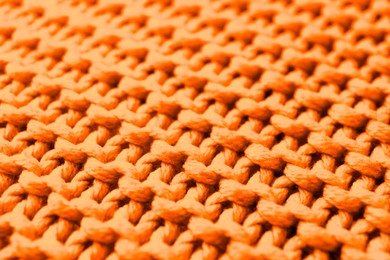 Soft orange knitted fabric as background, closeup