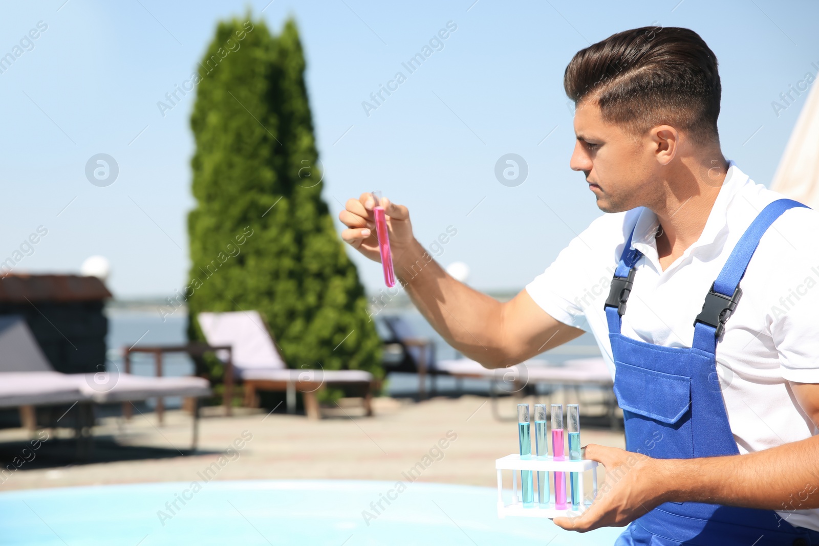 Photo of Man holding test tubes with reagents near swimming pool