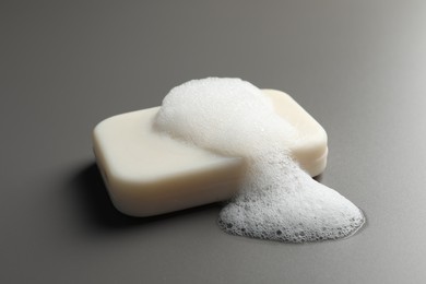 Photo of Soap with fluffy foam on grey background