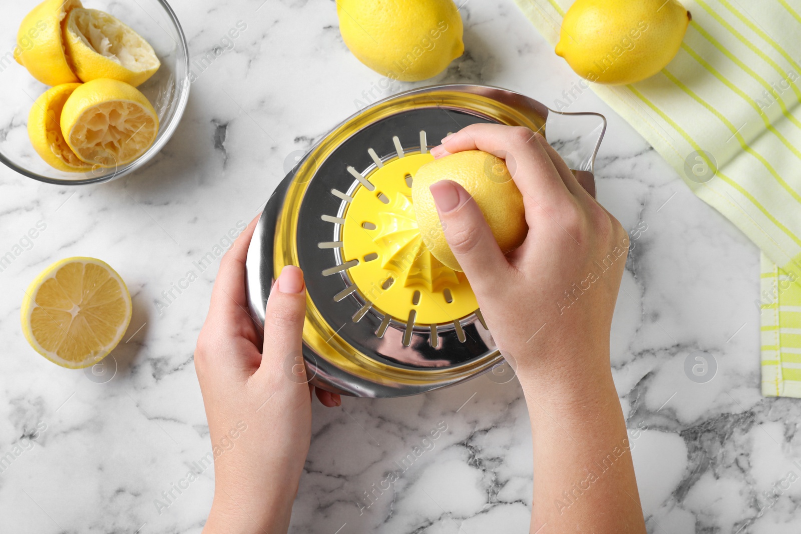 Photo of Woman squeezing lemon juice with reamer at white marble table, top view