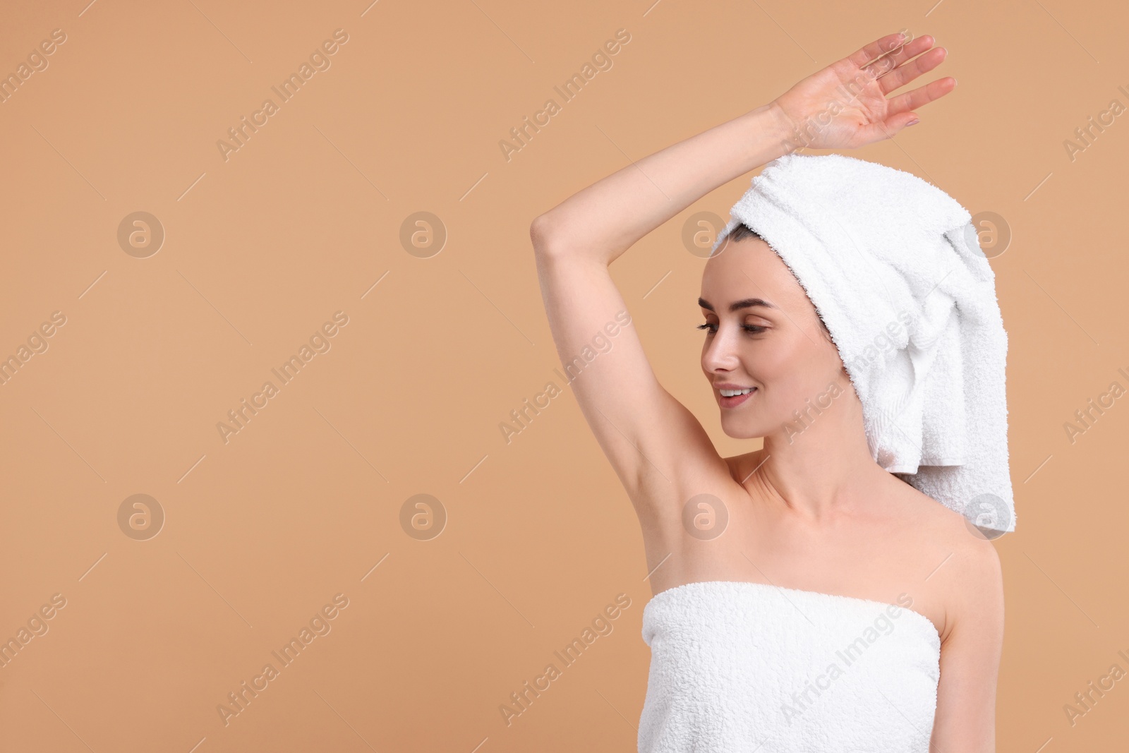 Photo of Beautiful woman showing armpit with smooth clean skin on beige background, space for text