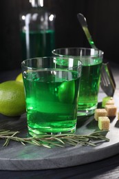 Absinthe in glasses, rosemary, brown sugar and lime on table. Alcoholic drink