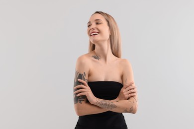 Portrait of beautiful tattooed woman on light background