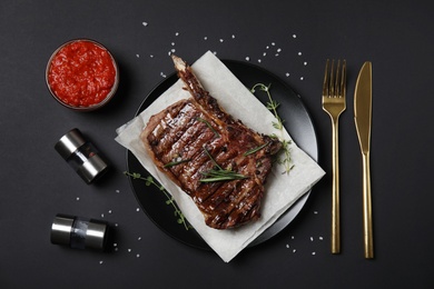 Flat lay composition with grilled meat steak on black background