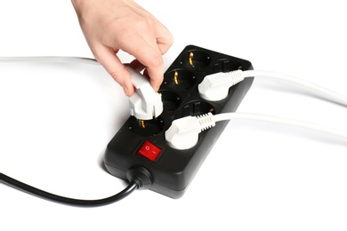 Photo of Woman putting plug into extension cord on white background, closeup. Electrician's equipment