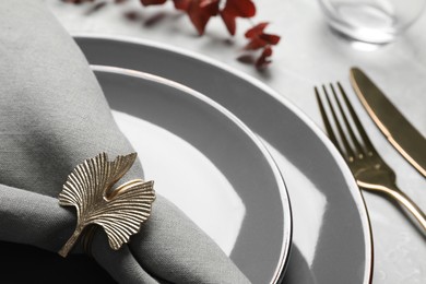 Fabric napkin and decorative ring for table setting on gray plate, closeup