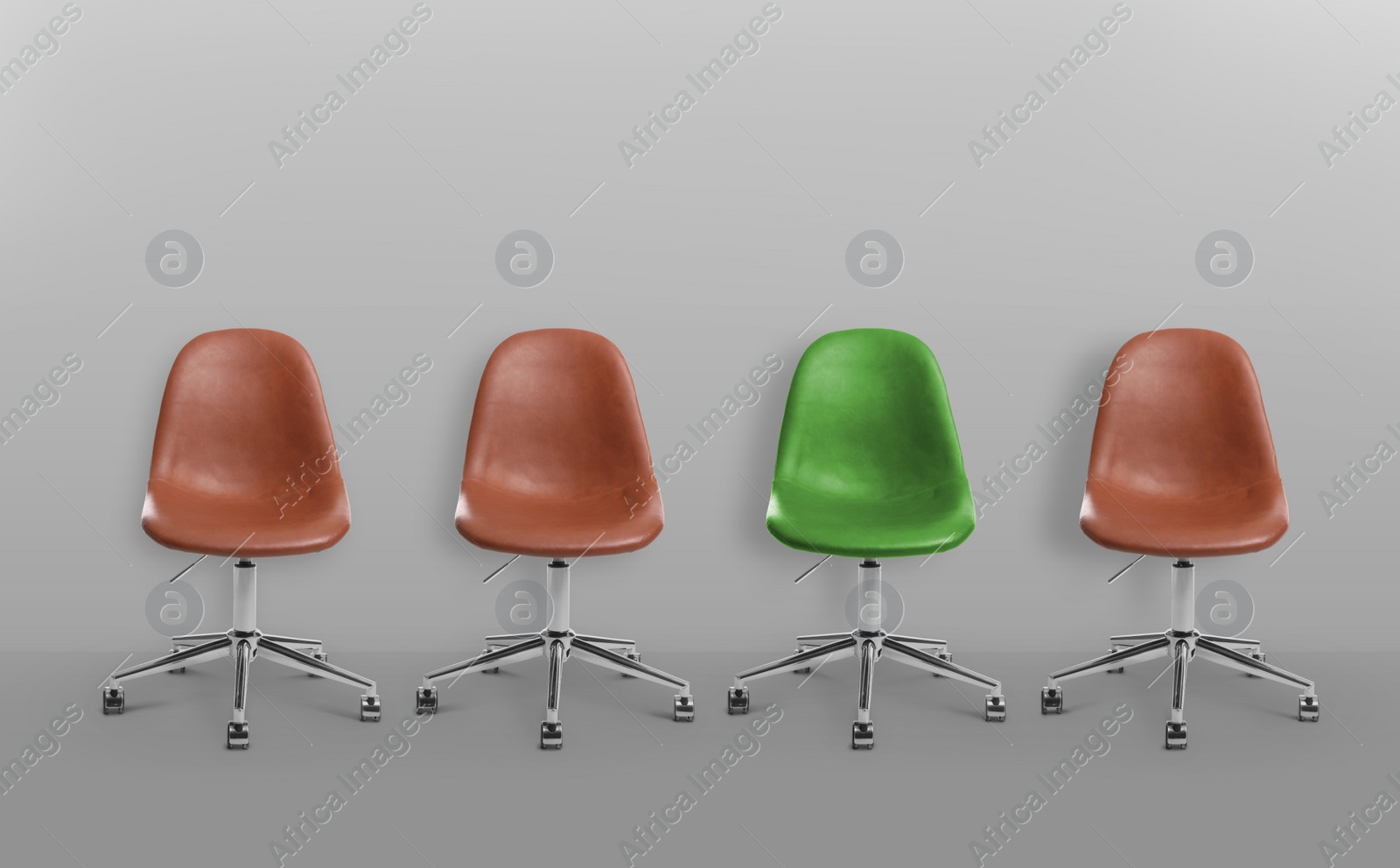 Image of Vacant position. Green office chair among brown ones on grey background