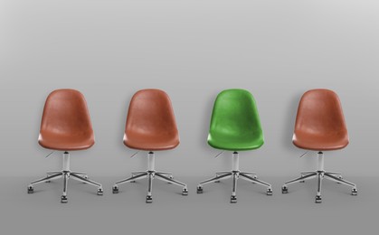 Image of Vacant position. Green office chair among brown ones on grey background