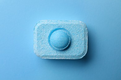 Photo of Water softener tablet on light blue background, top view