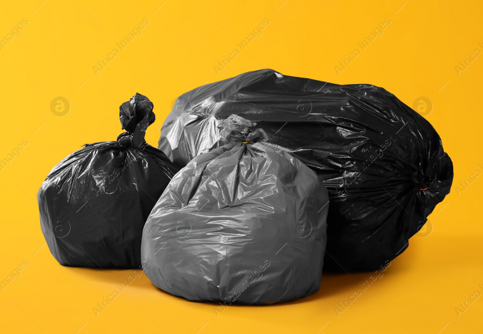 Photo of Trash bags full of garbage on yellow background