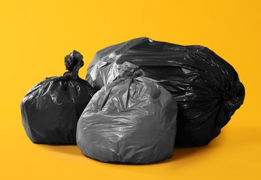 Photo of Trash bags full of garbage on yellow background