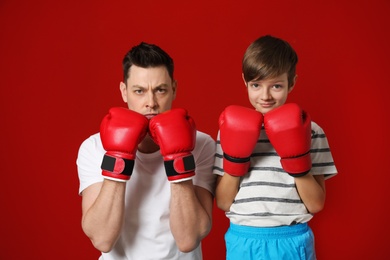 Photo of Dad and his son with boxing gloves on color background