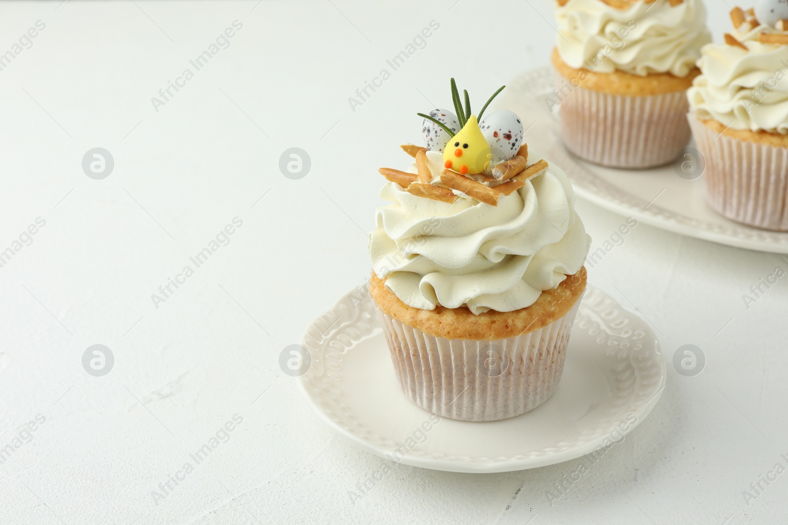 Photo of Tasty Easter cupcakes with vanilla cream on white table, space for text