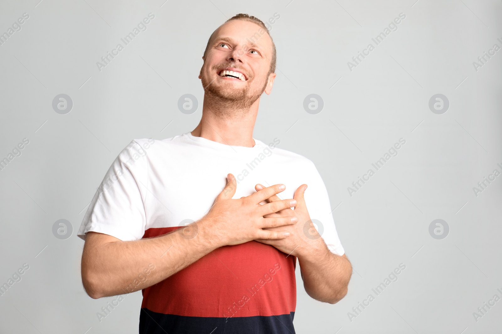 Photo of Portrait of man holding hands near heart on light background