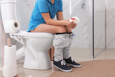 Photo of Boy holding toilet paper with blood stain in rest room, closeup. Hemorrhoid concept