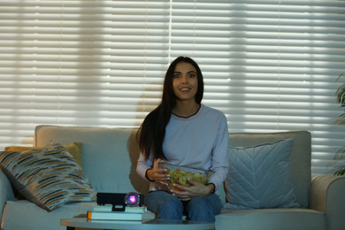 Young woman watching movie using video projector at home