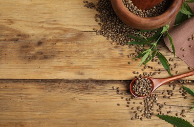 Flat lay composition with hemp seeds and leaves on wooden table. Space for text