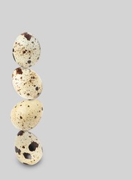 Stacked speckled quail eggs on light grey background. Space for text