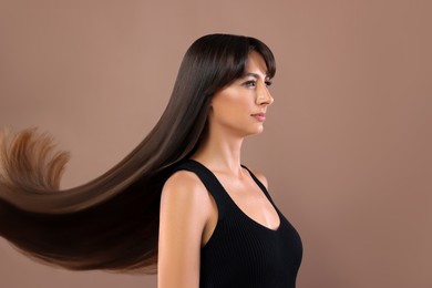 Image of Hair styling. Attractive woman with straight long hair on pale brown background