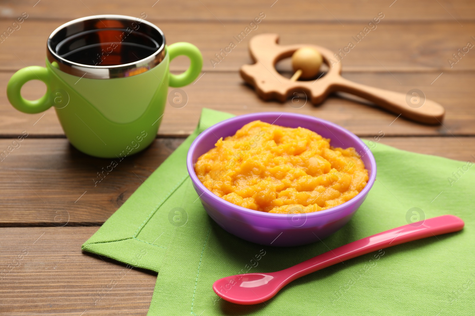 Photo of Plastic dishware with healthy baby food on wooden table