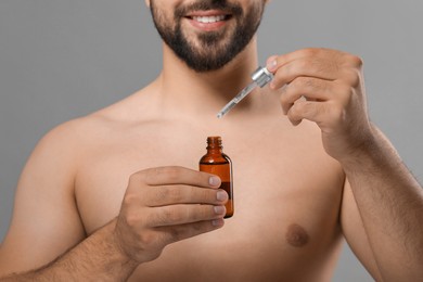 Photo of Man with cosmetic serum in hands on grey background, closeup