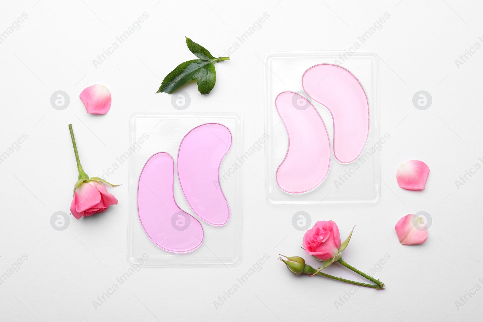 Photo of Packages with under eye patches and rose flowers on white background, flat lay. Cosmetic product