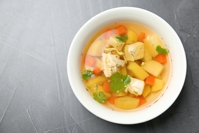 Photo of Homemade chicken soup in dish on grey background, top view with space for text