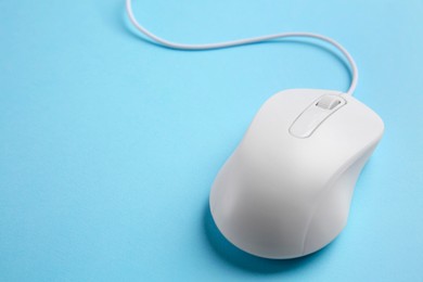 One wired mouse on light blue background, closeup. Space for text