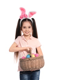 Photo of Little girl in bunny ears headband holding basket with Easter eggs on white background