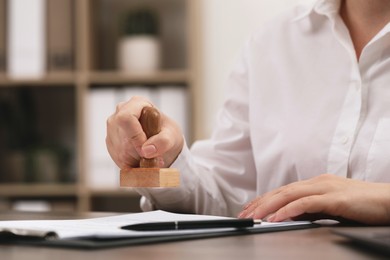 Woman stamping document at table, closeup view