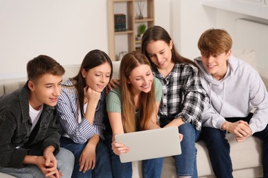 Photo of Group of happy teenagers using laptop in room at home