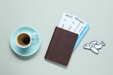 Flat lay composition with passport, tickets and cup of coffee on light grey table. Business trip