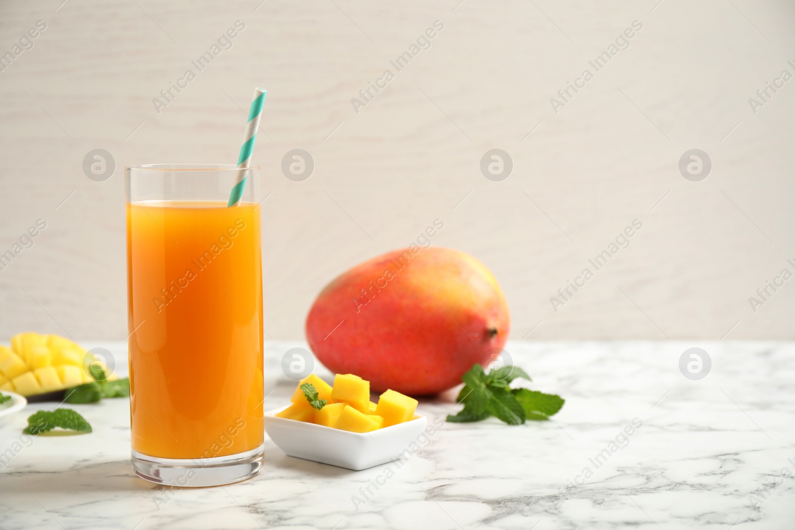 Photo of Fresh delicious mango drink on marble table. Space for text