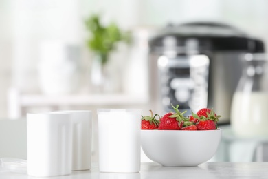 Cups for homemade yogurt and fresh strawberry on table in kitchen. Recipe for multi cooker