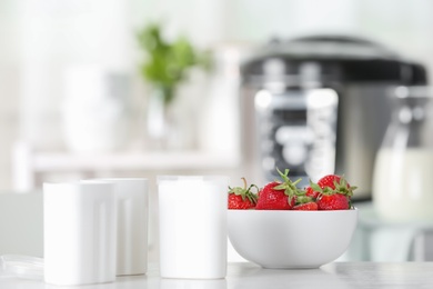 Photo of Cups for homemade yogurt and fresh strawberry on table in kitchen. Recipe for multi cooker