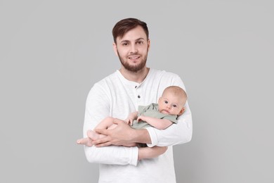 Photo of Father with his cute baby on grey background