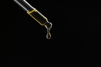 Photo of Dripping tincture from pipette on black background, closeup. Space for text