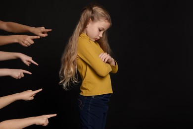 Photo of Kids pointing at upset girl on black background. Children's bullying