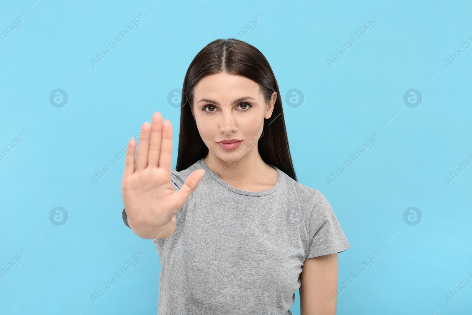 Photo of Woman showing stop gesture on light blue background