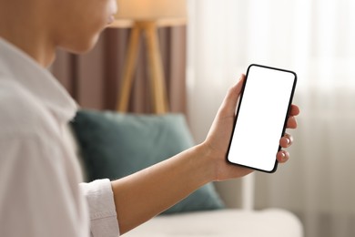 Man using smartphone with blank screen indoors, closeup. Mockup for design