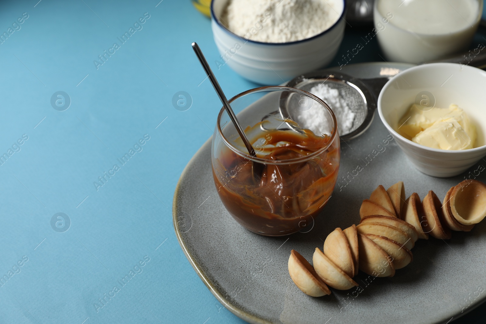 Photo of Ingredients for walnut shaped cookies on light blue table, flat lay. Space for text