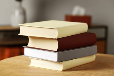 Many books stacked on wooden table indoors