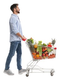 Young man with shopping cart full of groceries on white background