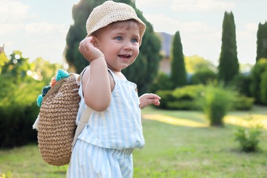 Photo of Cute little girl in stylish clothes with knitted backpack outdoors on sunny day. Space for text