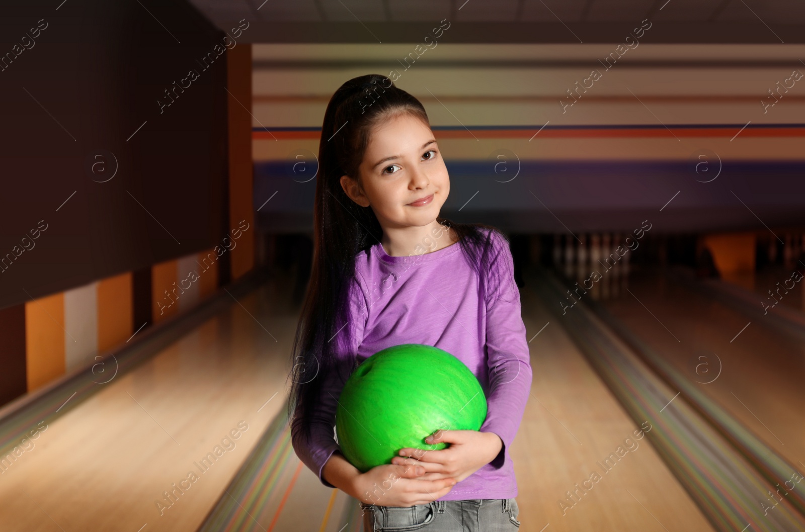 Photo of Little girl with ball in bowling club