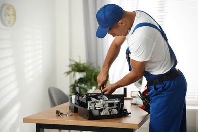 Photo of Repairman with screwdriver fixing modern printer in office