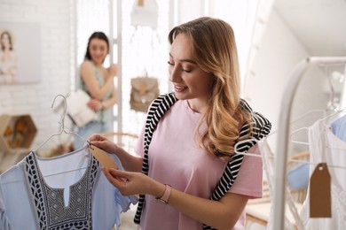 Photo of Woman choosing dress to buy in showroom